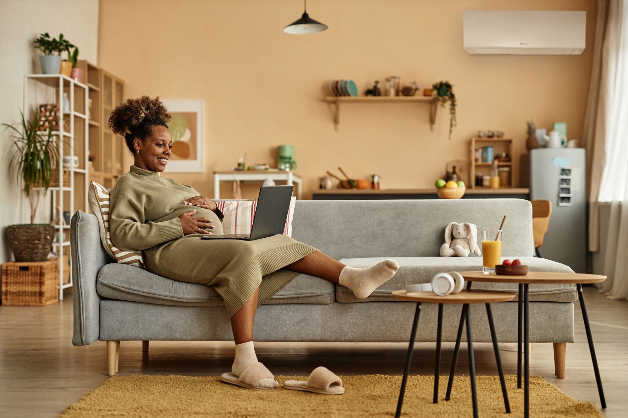 Pregnant mother on couch with Daikin Perfera on wall