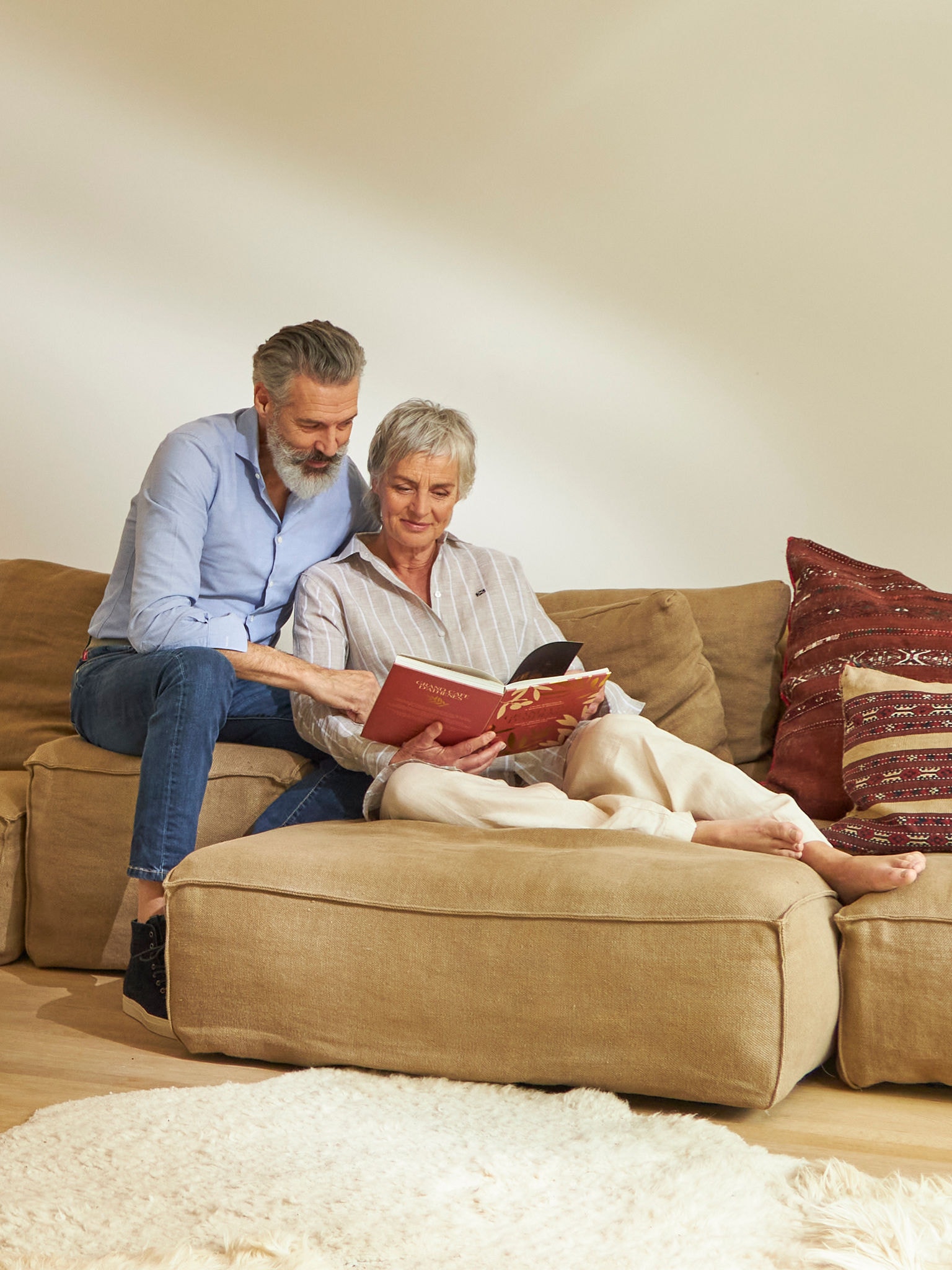 Midaldrende par, der læser og slapper af på deres sofa, mens de nyder den gode indendørs luftkvalitet.
