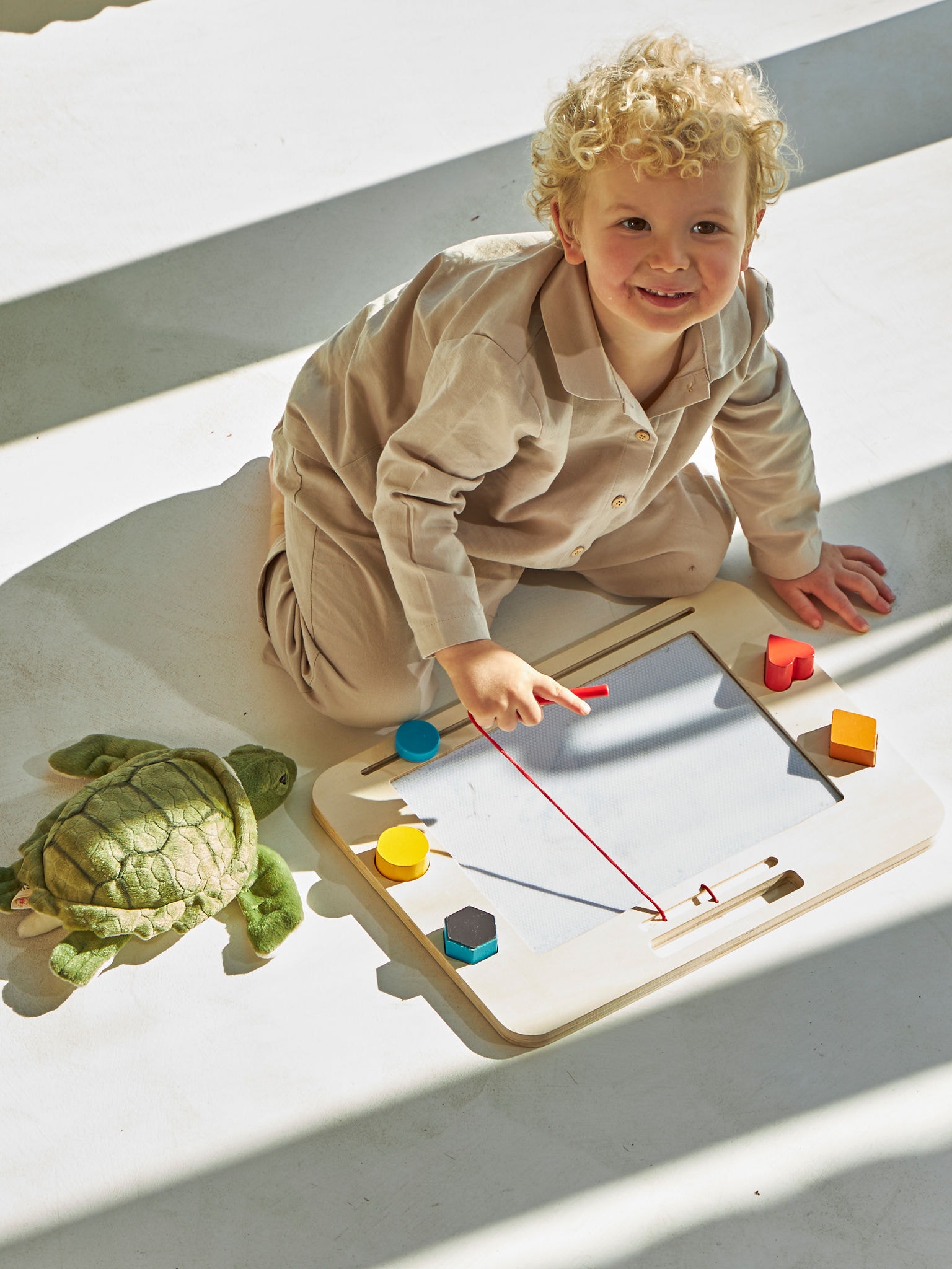 En lille dreng leger på gulvet og nyder gulvvarmen.