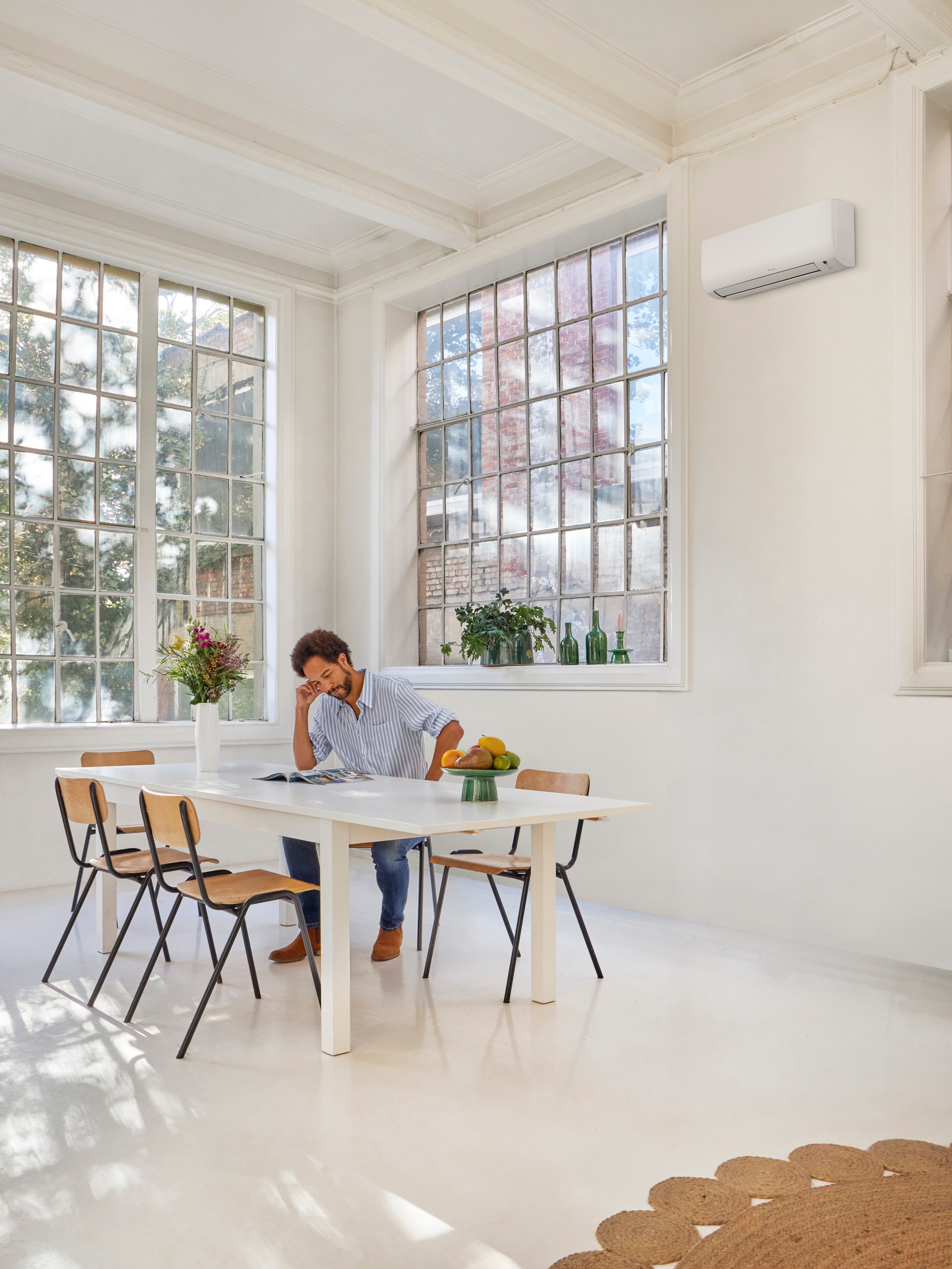 En mand læser ved bordet, mens han nyder den perfekte temperatur i sit hjem.
