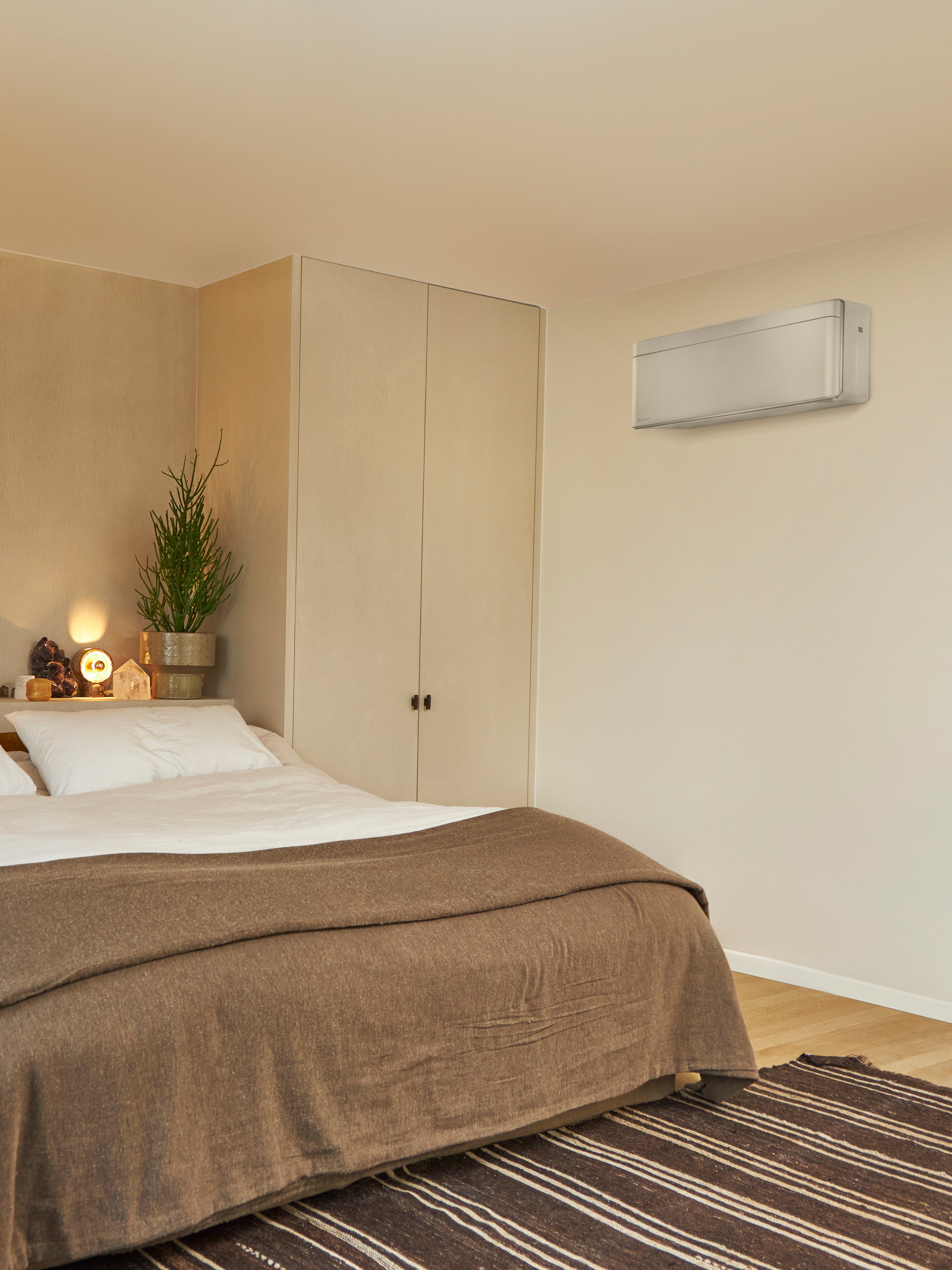 Stue med en stor seng og en vægmonteret klimaløsning.