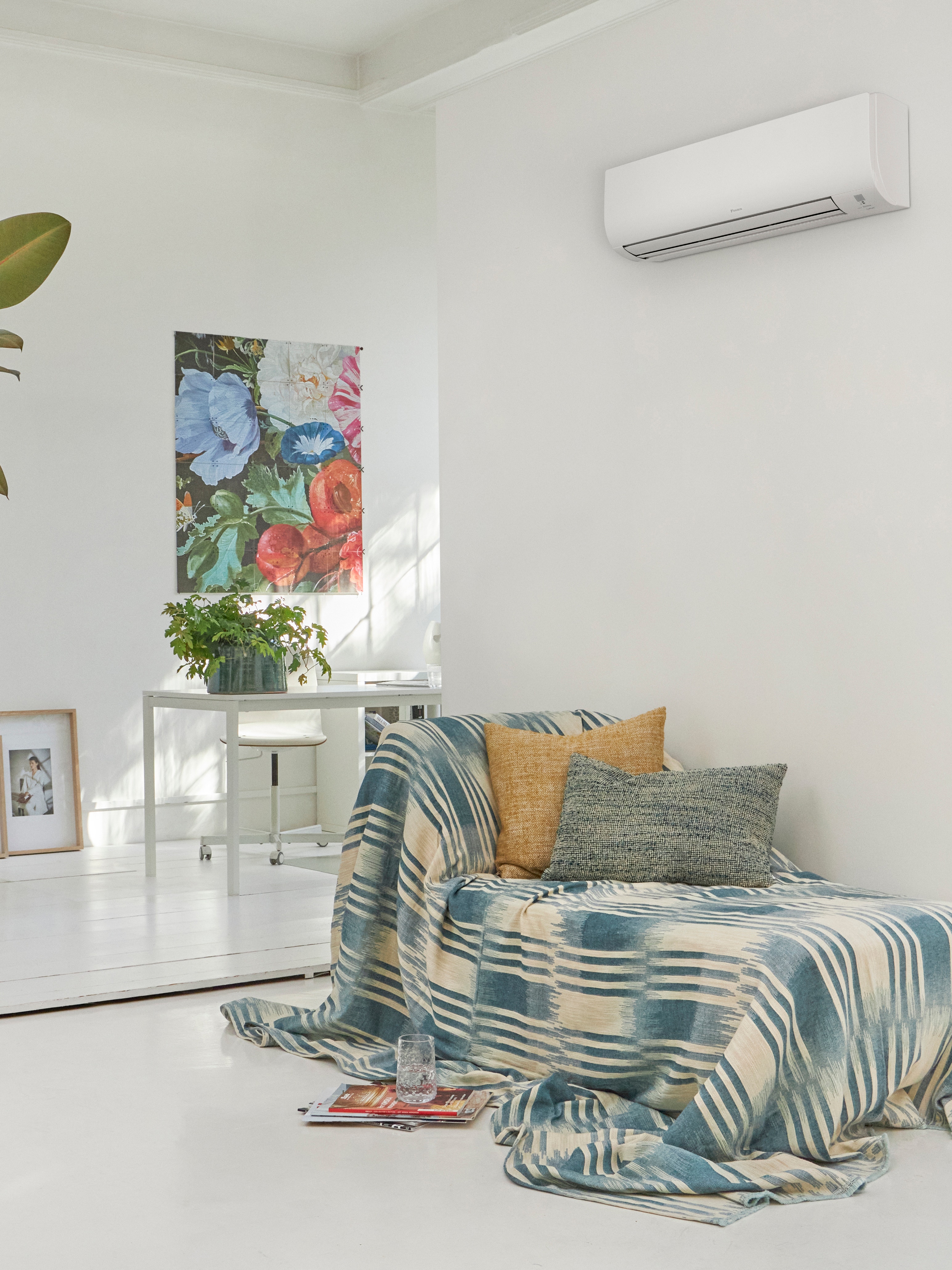 Hvid stue med en sofa, der er placeret under en vægmonteret klimaløsning.