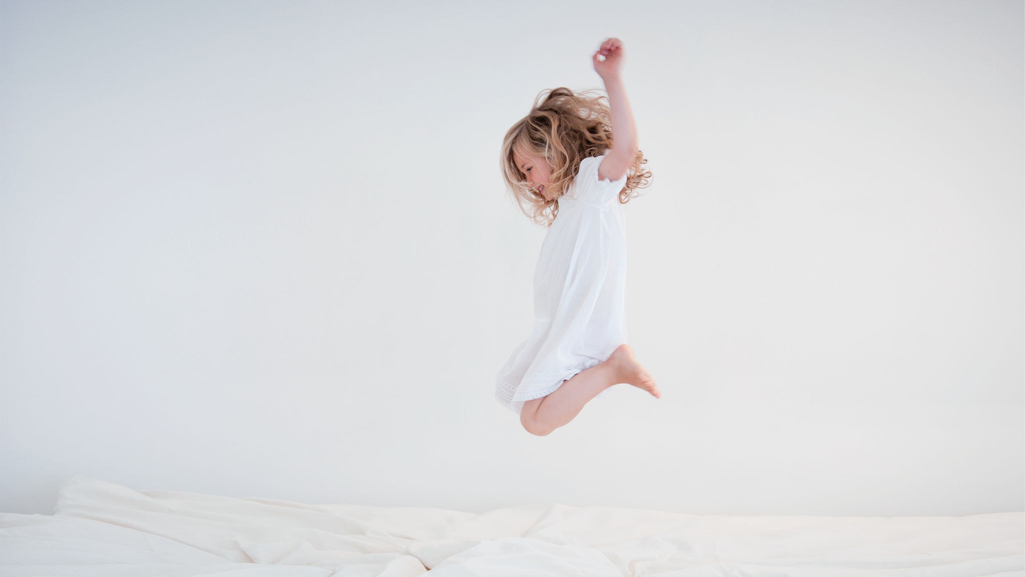 Et barn hopper i sengen og nyder den rene og friske luft.
