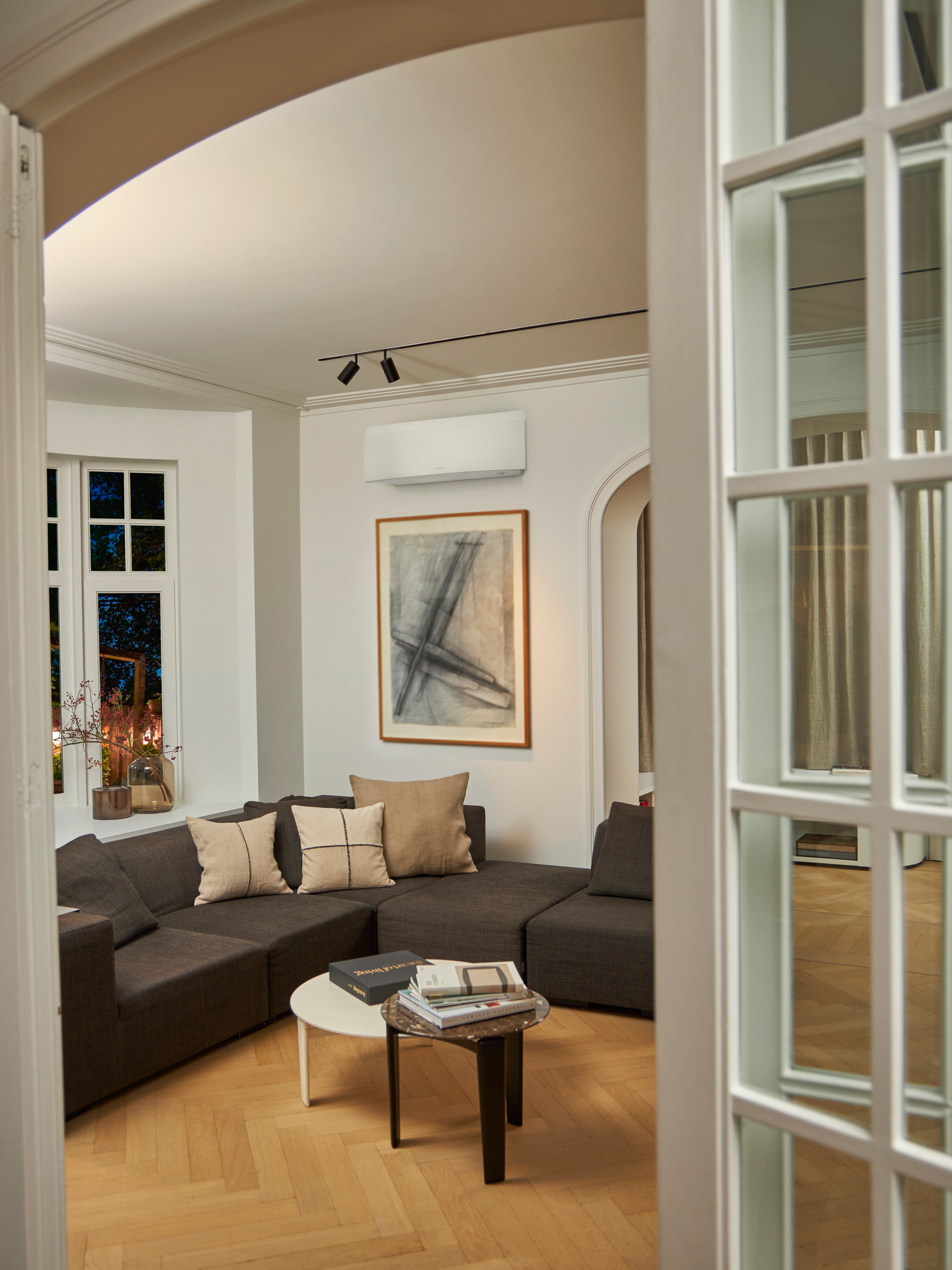 Stue med en sofa, der er placeret under en vægmonteret klimaløsning.