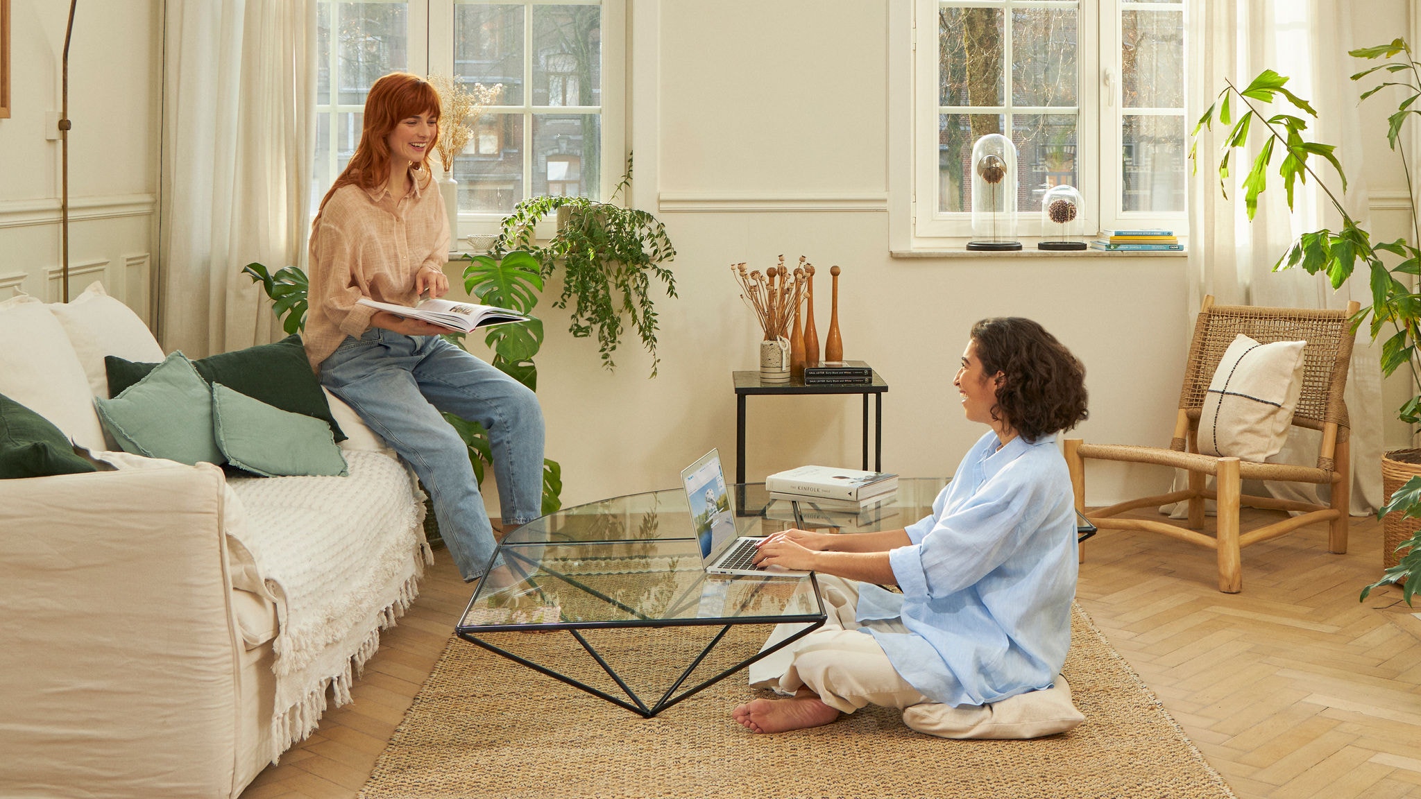 To kvinder, der griner i stuen, mens de arbejder og læser.